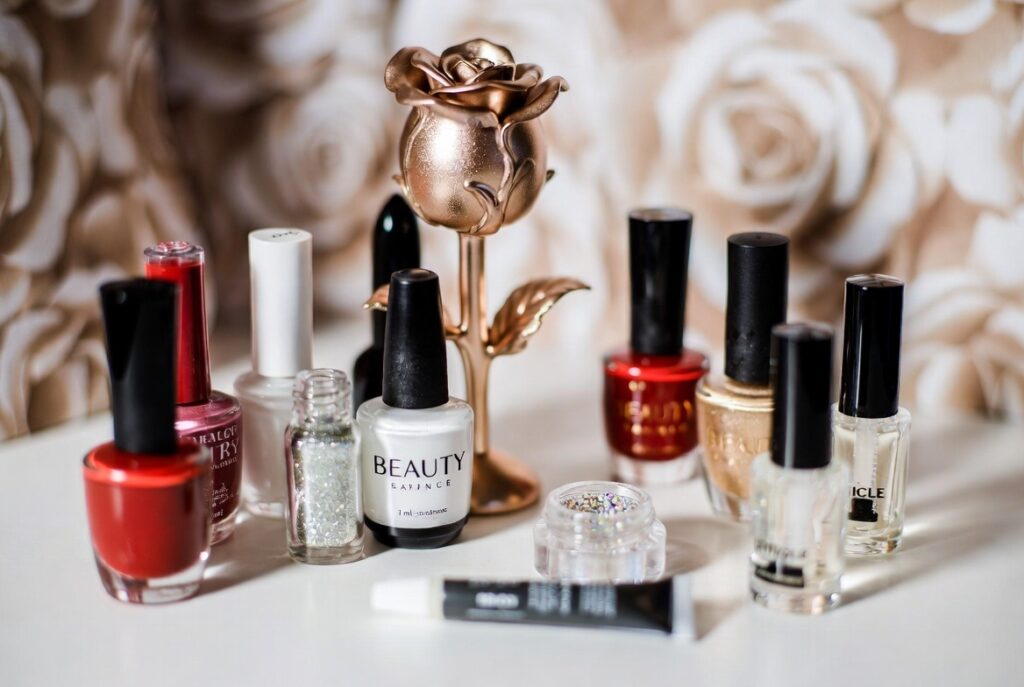 Beauty and the Beast nail ideas 2026 featuring dramatic coffin-shaped acrylic nails with intricate 3D enchanted rose designs in deep red and gold on a dark background with green leaves and stems