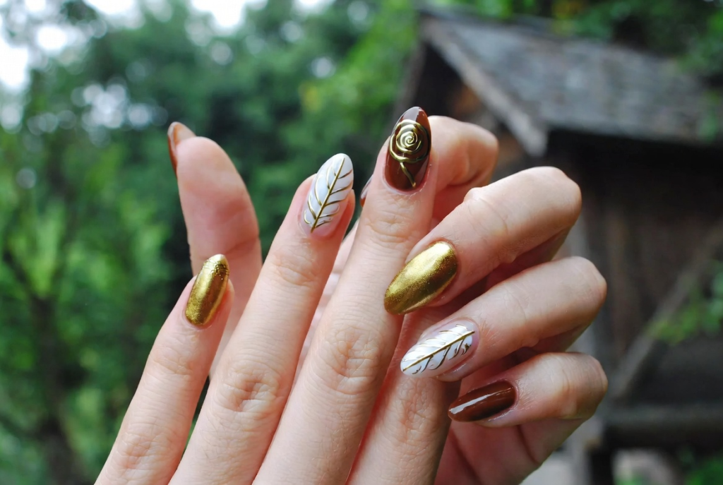 Beauty and the Beast nail ideas 2026 featuring dramatic coffin-shaped acrylic nails with intricate 3D enchanted rose designs in deep red and gold on a dark background with green leaves and stems