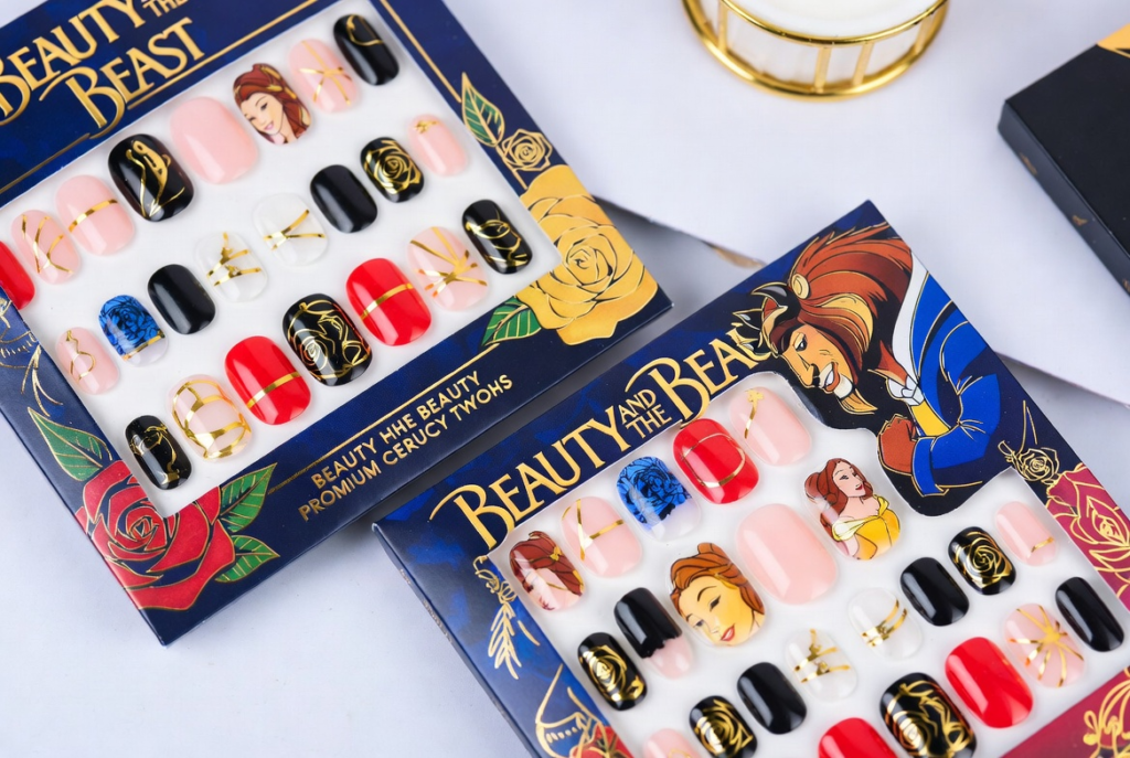 Beauty and the Beast nail ideas 2026 featuring dramatic coffin-shaped acrylic nails with intricate 3D enchanted rose designs in deep red and gold on a dark background with green leaves and stems