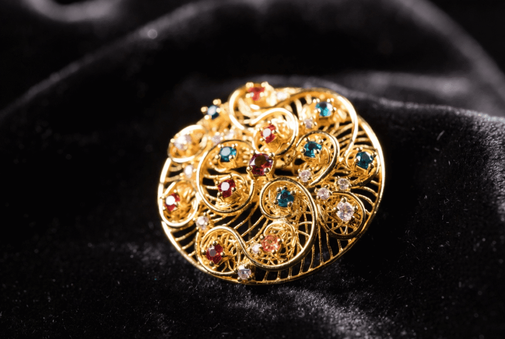 A stunning collection of brooch aesthetic jewelry featuring vintage gold cameos, modern crystal statement pieces, and pearl clusters artfully arranged on soft velvet. The display captures the timeless elegance and diversity of brooch design for ladies, from heirloom treasures to luxury designer brooches.